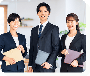 スーツを着た女性2名と男性1名が正面を見て微笑んでいる