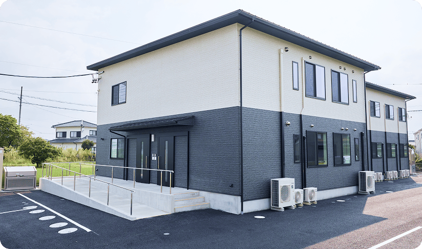スロープ付き入口の二階建て施設外観（晴天）